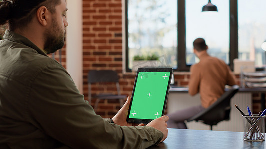 平板电脑绿幕摄影照片_男性自由职业者持有带绿屏显示的数字平板电脑
