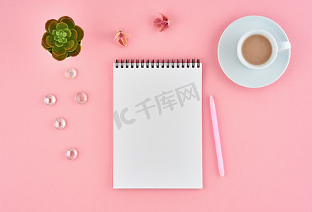 空白记事本白页和粉红色办公桌上的可可杯，彩色背景。