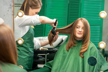 美发师一边用梳子梳头一边为女人做发型，在美发沙龙梳头。