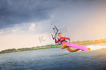 一位年轻的女子风筝冲浪者乘风破浪做把戏。