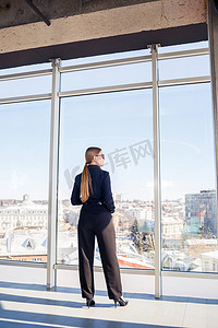 女脸手摄影照片_自信的女商人老板站在现代办公室或酒店的窗户里，欣赏大城市的景色，女领导，企业主思考未来的成功，规划新的机会，