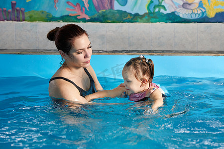 小孩子和老师一起在游泳池里学习游泳