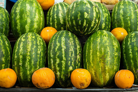 黄色西瓜摄影照片_市场上成排的新鲜水果