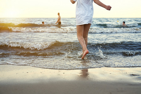 穿着泳装的女孩正在沙滩上玩海浪-跳跃、奔跑、玩乐。