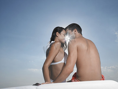 浪漫的年轻夫妇的后视图，阳光照在游艇上的脸庞之间