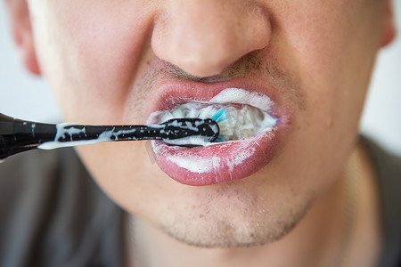 一个男人用电动牙刷刷牙。
