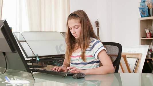坐在电脑前办公桌前的幼儿打在线作业