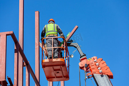 男性建筑工人在升降摇篮中高空作业，打造建筑物的铁架