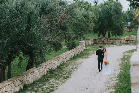 幸福天降摄影照片_幸福时尚微笑的夫妇在婚礼当天在意大利托斯卡纳散步。