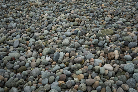 彩色背景海边摄影照片_海滨自然背景纹理图案上的天然圆形砾石。