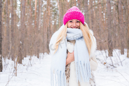 美丽、冬天和人的概念 — 在白雪皑皑的森林里，穿着粉色毛衣的金发美女微笑着