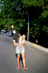 妈妈抱着小女孩走在路上