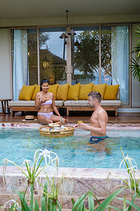 度假期间，一对男女在泳池别墅的泳池里吃早餐