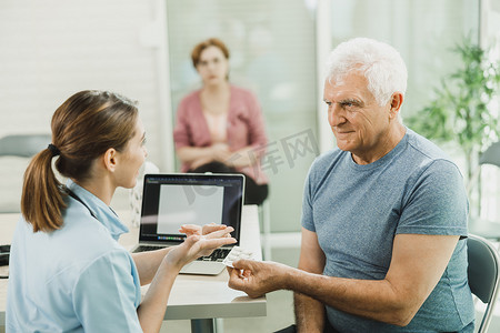 有爱心的护士在医院候诊室与老人交谈