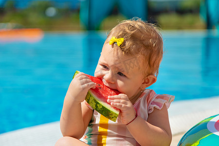 西瓜大海摄影照片_宝宝正在泳池边吃西瓜。