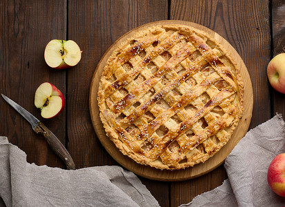 圆形烤馅饼，木板上有苹果馅，棕色的桌子上。