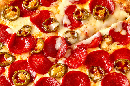 意大利辣味香肠摄影照片_辣味意大利辣香肠披萨上放上墨西哥胡椒片，配上融化的马苏里拉奶酪