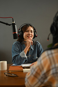 友好的电台主持人戴着耳机与她的客人讨论各种话题，同时从家庭工作室流式传输现场音频播客