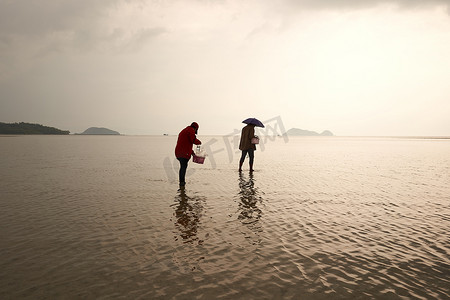 保护海洋日摄影照片_2022年3月15日，泰国帕岸岛：两名采集蛤蜊的妇女的剪影