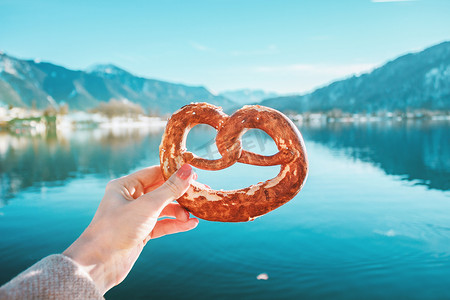 在德国巴伐利亚阿尔卑斯山的山湖背景上手拿传统面包。