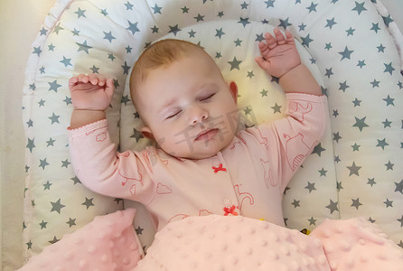 床上睡觉的婴儿摄影照片_宝宝睡在粉红色的床上。