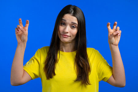 语言摄影照片_漂亮的女人用手和两个手指展示空气引用手势，弯曲手指隔离在蓝色背景。