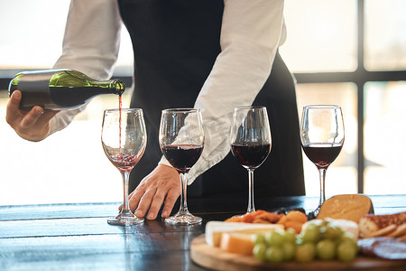 热情红色摄影照片_豪华、精致的餐饮和热情好客，服务员在餐厅倒红酒。