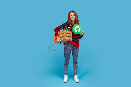 妇女拿着装有空塑料瓶和绿色回收标志的盒子，与环境问题作斗争。