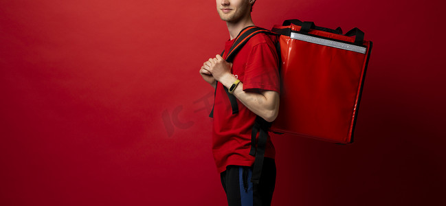 年轻英俊、快乐微笑的快递员，带着红色保温箱送餐的送餐员。