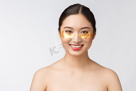 护肤品金色摄影照片_亚洲美女少女在眼睛下方用金色眼罩贴片护理皮肤