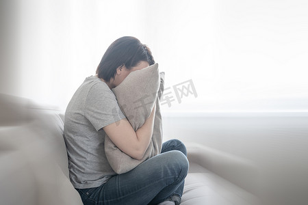 枕头摄影照片_悲伤抑郁的女人在枕头上哭泣，孤独和悲伤的概念与运动模糊效果