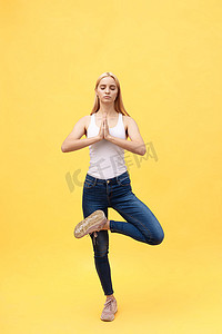 青少年照片摄影照片_穿着白色运动服的运动迷人的年轻女子正在做脊柱锻炼，摆出 Vrikshasana 姿势，双手举过头顶，做 Anjali mudra，大型照片系列的一部分，孤立，全长。