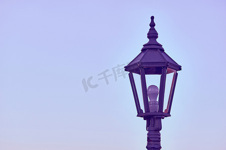 带 LED 灯泡和傍晚蓝色平静天空的孤独紫色灯笼