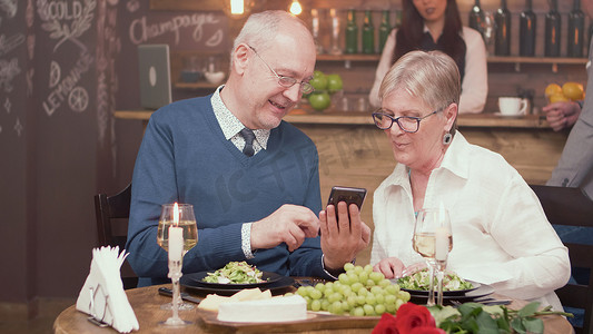 老人在餐厅里向妻子展示手机上的东西