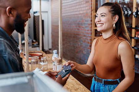 快乐的西班牙裔顾客使用 NFC 机和信用卡在餐厅付款。
