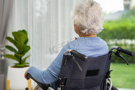 卫生设施摄影照片_一位坐在轮椅上的老妇人望着窗外等人。