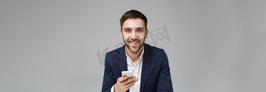 经营理念-肖像英俊快乐英俊的商人穿着西装玩手机，在工作办公室用笔记本电脑微笑。