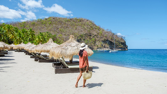在圣卢西亚热带海滩上散步的年轻女子，在加勒比海白色海滩上种植棕榈树的女孩