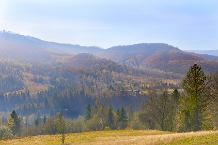山谷中的秋季小村庄和蓝色薄雾中的山脉