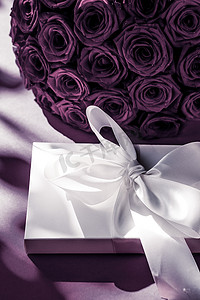 豪华假日丝绸礼盒和紫色背景的玫瑰花束、浪漫惊喜和鲜花作为生日或情人节礼物