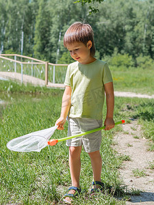 小孩带着蝴蝶网到户外散步。