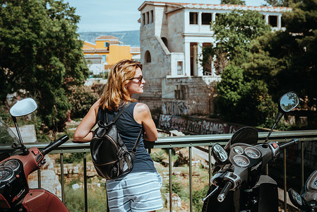 美丽的女孩走在希腊首都雅典的一个古老的欧洲小镇的街道上。