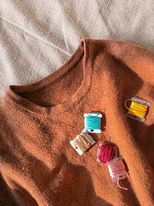 土色羊毛衫和彩色刺绣线线圈的顶视图。