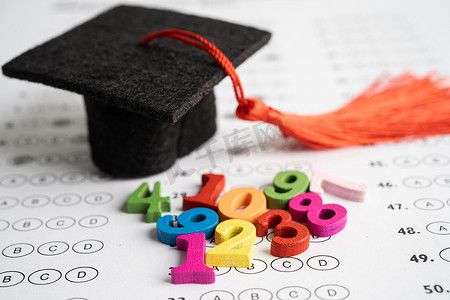 数学孩子摄影照片_数学数字与毕业帽和铅笔在答题纸背景上五颜六色，教育学习数学学习教学概念。