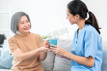 女护理员为心满意足的老年患者提供一杯咖啡。