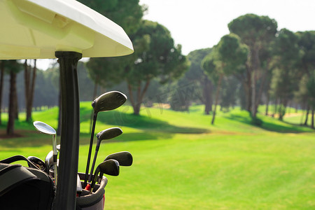 高尔夫球包摄影照片_在一个美丽的高尔夫球场上，高尔夫球车后面的高尔夫球袋里放着一组高尔夫球杆