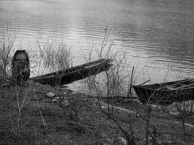 古老木船摄影照片_两艘古老的木船停泊在河岸上。