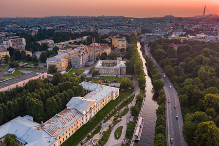日落时，俄罗斯圣彼得堡卡尔波夫卡河堤公园的鸟瞰图、休闲区、长椅和圆形剧场、公园对面的植物园