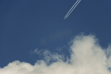 有尾迹的飞机飞向蓝天蓬松的积云