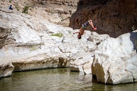 进入水里摄影照片_在阿曼沙漠中部的绿洲里，运动型的家伙从悬崖上后空翻进入湖中